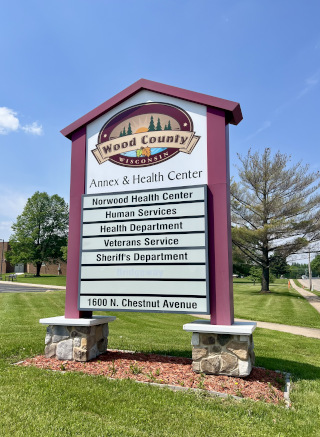Wood County Annex and Health Center outdoor sign, listing Norwood Health Center, Human Services, Health Department, Veterans Service, Sheriff's Department, and Bridgeway.